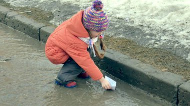 Lastik kız wite kağıt tekne yakınındaki su birikintisi atlama botlar