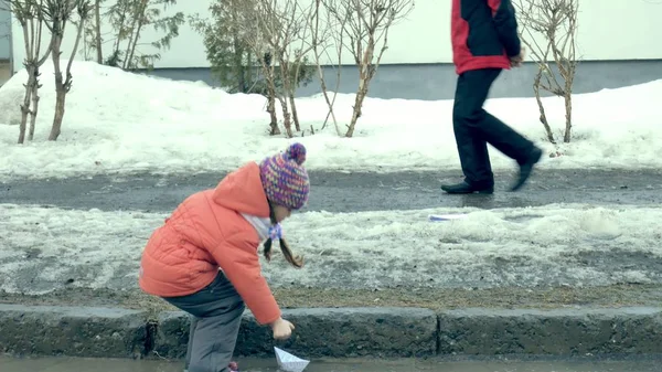 Lastik kız wite kağıt tekne yakınındaki su birikintisi atlama botlar — Stok fotoğraf