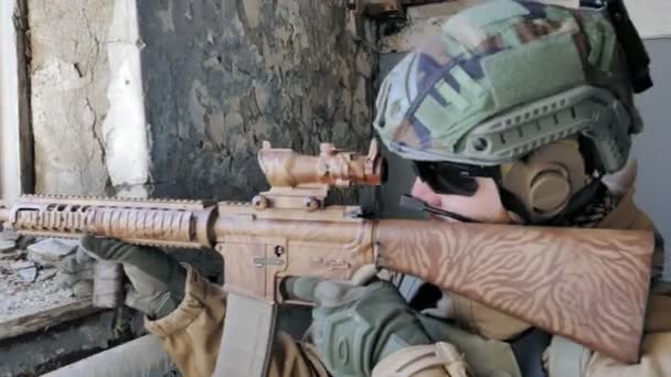 Soldiers in camouflage with a military weapon aiming through the rifle sight through the window of an old building, the military concept — Stock Video