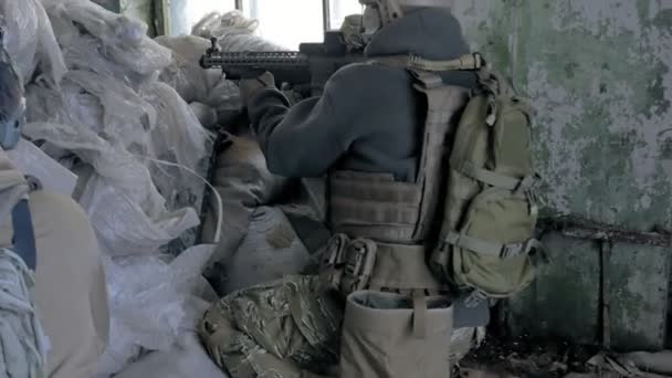 Soldados en camuflaje con armas de combate están siendo disparados en el refugio del viejo edificio, el concepto militar — Vídeo de stock