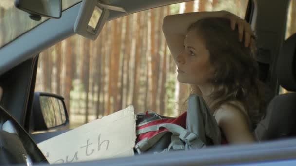 Jeune belle femme auto stop debout sur la route avec un sac à dos sur une table avec une inscription SUD dans une voiture — Video