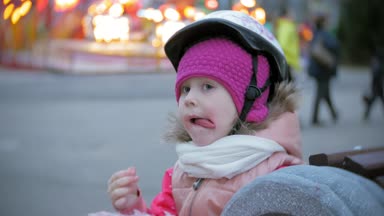 Pembe Tatlı pamuk şeker tekerlekli paten üzerinde haddeleme lunaparktaki, bir bankta oturmuş güzel küçük kız