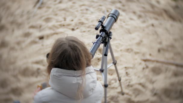 Femme attirante regarde à travers un télescope dans une forêt sur la rive de la rivière — Video