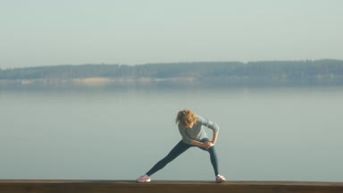 Genç fitness kadının açık salonda nehir kıyısında egzersizleri yapması