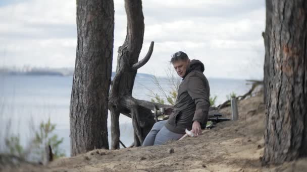 Viejo mira a través de un telescopio en un bosque en la orilla del río — Vídeos de Stock