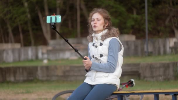 Bonito menina sorriso tirar auto foto selfie com telefone inteligente móvel no parque — Vídeo de Stock