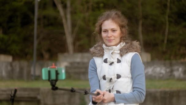 Bonito menina sorriso tirar auto foto selfie com telefone inteligente móvel no parque — Vídeo de Stock