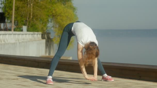 Unga fitness kvinna gör övningar på gymmet i en utomhus på Älvstranden — Stockvideo