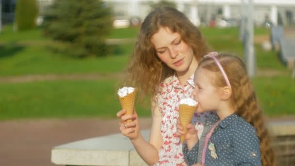 ママと娘が公園でアイスクリームを食べるします。母と子。リラックスした幸せ家族 — ストック動画