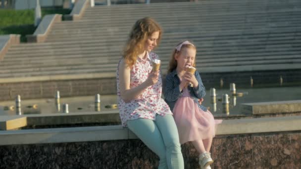 Anya és lánya eszik fagylaltot egy parkban. anya és gyermeke. pihentető boldog család — Stock videók