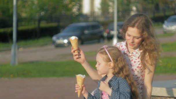 Mamá e hija comiendo helado en un parque. madre e hijo. relajante familia feliz — Vídeo de stock