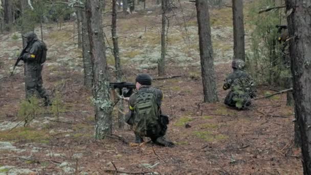 Soldados en camuflaje con armas de combate están siendo disparados en el refugio del bosque, el concepto militar — Vídeo de stock