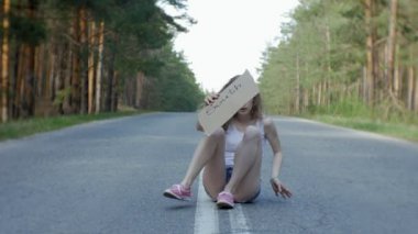 Yolda bir sırt çantası bir tablo ile bir yazıt güneye otostop kalan genç güzel kadın