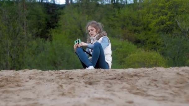 Hezká dívka úsměv si vlastní obrázek selfie s chytrý telefon mobilní na břehu řeky — Stock video