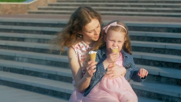 Mom and daughter eating ice cream in a park. mother and child. relaxing happy family — Stock Video