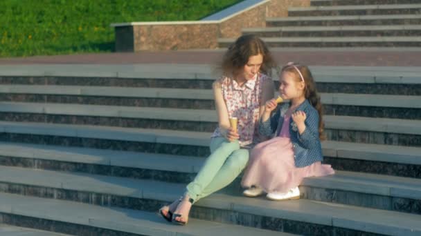 Mom and daughter eating ice cream in a park. mother and child. relaxing happy family — Stock Video