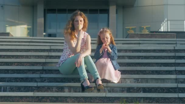 Moeder en dochter eten van ijs in een park. moeder en kind. ontspannen en gelukkige familie — Stockvideo