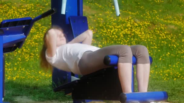 Unga fitness kvinna gör övningar på gymmet i en utomhus park — Stockvideo