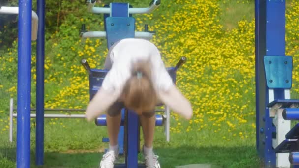 Unga fitness kvinna gör övningar på gymmet i en utomhus park — Stockvideo