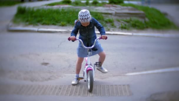Pequena menina bonita está montando uma bicicleta — Vídeo de Stock