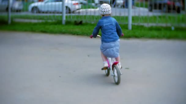 Pequena menina bonita está montando uma bicicleta — Vídeo de Stock