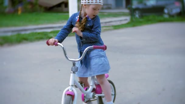 Маленькая красивая девочка едет на велосипеде — стоковое видео