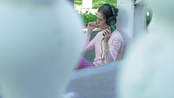 Joven mujer hermosa con estilo, en las calles de la ciudad escuchando música en los auriculares del monitor grande . — Vídeos de Stock