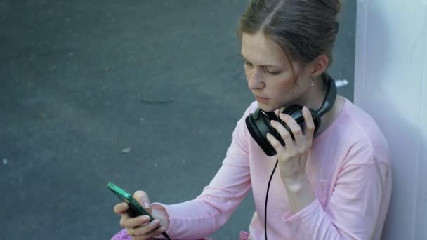 대형 모니터 헤드폰에서 음악을 듣고 하는 도시의 거리에서 젊은 세련 된 아름 다운 여자. — 비디오