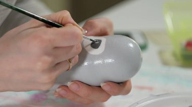 Bir kadın bir ahşap bebek renkli boyalar ile ev stüdyosunda, boyalar Matryoshka boyama, yakın çekim