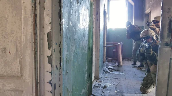 Katonák a harci fegyverek álcázás settenkedik a folyosókon, a régi épület, a katonai koncepció mentén — Stock Fotó