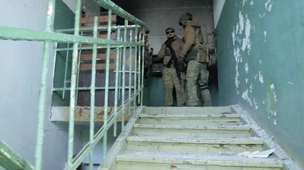 Soldados em camuflagem com armas de combate esgueiram-se pelos corredores do antigo edifício, o conceito militar — Fotografia de Stock