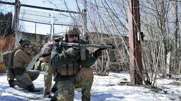 Soldaten in Tarnanzügen mit Kampfwaffen bahnen sich ihren Weg vor das alte Gebäude, um es zu erobern, das militärische Konzept — Stockfoto