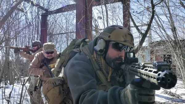 Soldaten in Tarnanzügen mit Kampfwaffen bahnen sich ihren Weg vor das alte Gebäude, um es zu erobern, das militärische Konzept — Stockfoto