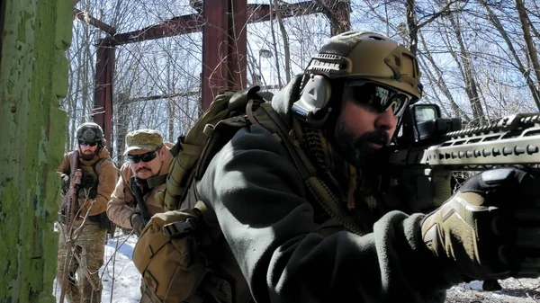 Soldados em camuflagem com armas de combate saem do antigo prédio, com o objetivo de capturá-lo, o conceito militar. — Fotografia de Stock