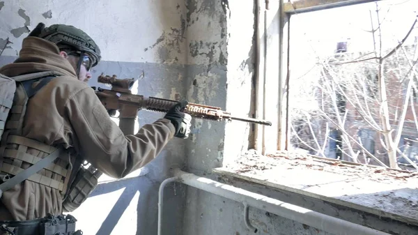 Soldados em camuflagem com uma arma militar apontando através da mira do rifle através da janela de um edifício velho, o conceito militar — Fotografia de Stock