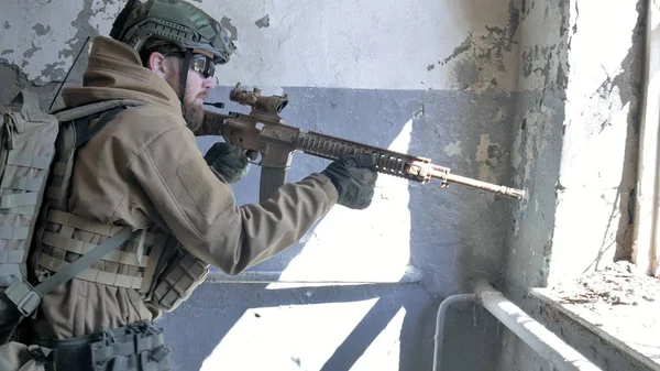 Soldaten in Tarnung mit einer Militärwaffe, die durch das Fenster eines alten Gebäudes auf das Gewehr zielte, das militärische Konzept — Stockfoto