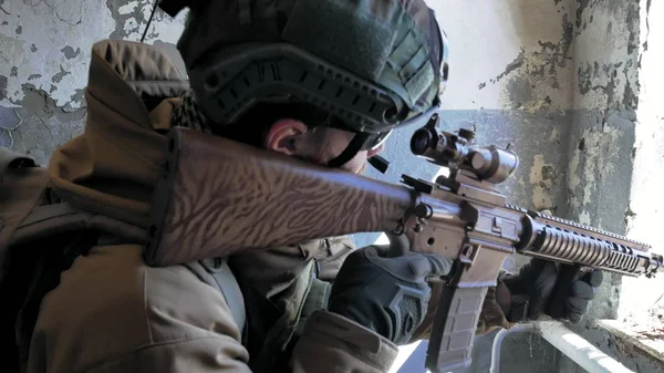 Soldaten in camouflage met een militaire wapen gericht door middel van het geweer zicht door het raam van een oud gebouw, het militaire concept — Stockfoto