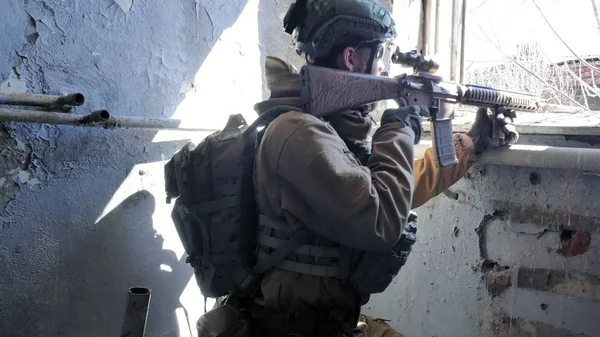 Soldaten in Tarnung mit einer Militärwaffe, die durch das Fenster eines alten Gebäudes auf das Gewehr zielte, das militärische Konzept — Stockfoto