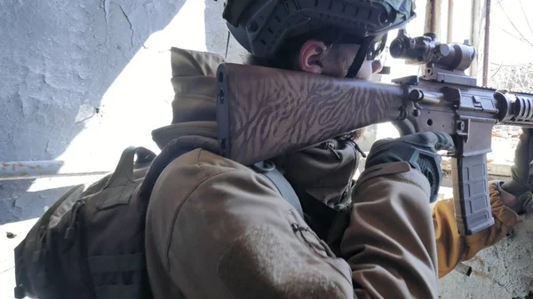 Soldaten in Tarnung mit einer Militärwaffe, die durch das Fenster eines alten Gebäudes auf das Gewehr zielte, das militärische Konzept — Stockfoto