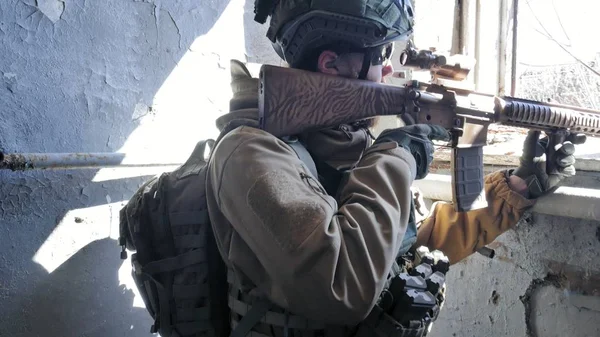 Soldaten in Tarnung mit einer Militärwaffe, die durch das Fenster eines alten Gebäudes auf das Gewehr zielte, das militärische Konzept — Stockfoto