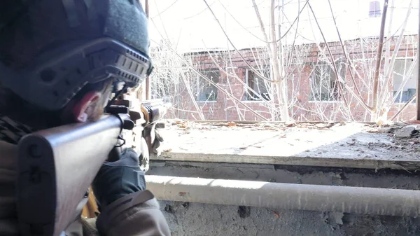 Soldados en camuflaje con un arma militar apuntando a través de la mira del rifle a través de la ventana de un viejo edificio, el concepto militar —  Fotos de Stock