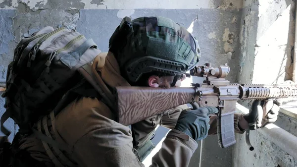 Soldaten in Tarnung mit einer Militärwaffe, die durch das Fenster eines alten Gebäudes auf das Gewehr zielte, das militärische Konzept — Stockfoto