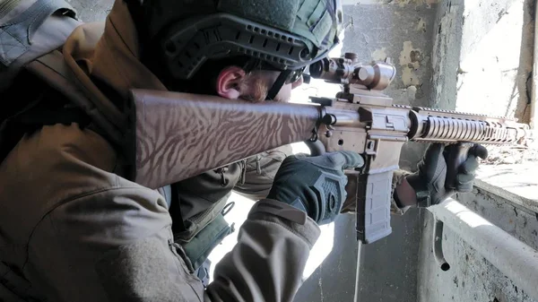 Soldaten in Tarnung mit einer Militärwaffe, die durch das Fenster eines alten Gebäudes auf das Gewehr zielte, das militärische Konzept — Stockfoto