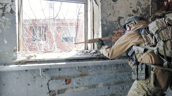 Солдаты в камуфляже с военным оружием, нацеленным через прицел винтовки через окно старого здания, военная концепция — стоковое фото