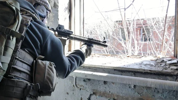 Soldados en camuflaje con un arma militar apuntando a través de la mira del rifle a través de la ventana de un viejo edificio, el concepto militar — Foto de Stock