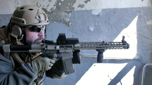 Soldados en camuflaje con un arma militar apuntando a través de la mira del rifle a través de la ventana de un viejo edificio, el concepto militar — Foto de Stock