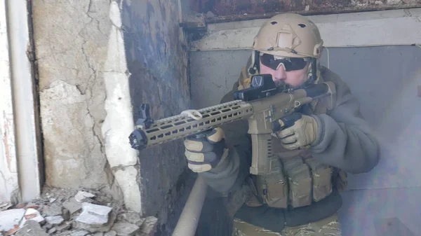 Soldaten in Tarnung mit einer Militärwaffe, die durch das Fenster eines alten Gebäudes auf das Gewehr zielte, das militärische Konzept — Stockfoto