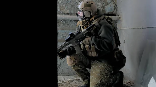 Soldaten in Tarnung mit einer Militärwaffe, die durch das Fenster eines alten Gebäudes auf das Gewehr zielte, das militärische Konzept — Stockfoto