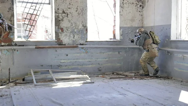 Soldados en camuflaje con un arma militar apuntando a través de la mira del rifle a través de la ventana de un viejo edificio, el concepto militar — Foto de Stock