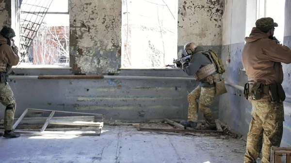 Soldiers in camouflage with a military weapon aiming through the rifle sight through the window of an old building, the military concept — Stock Photo, Image